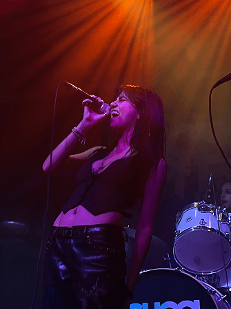 Neta singing on stage under orange and purple lights